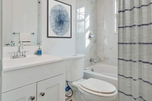 A white bathroom with a toilet, sink, and shower curtain.
