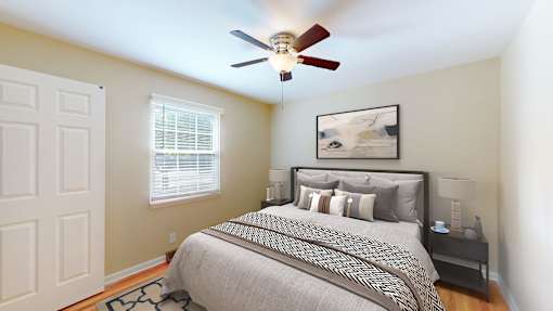 A bedroom with a bed, nightstand, and a ceiling fan.