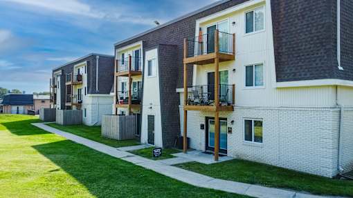A row of modern townhouses with balconies and green lawns.