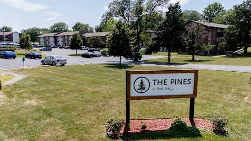 A sign for The Pines at Red Bridge stands in a grassy field.