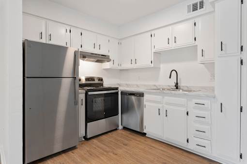 A modern kitchen with white cabinets and stainless steel appliances.
