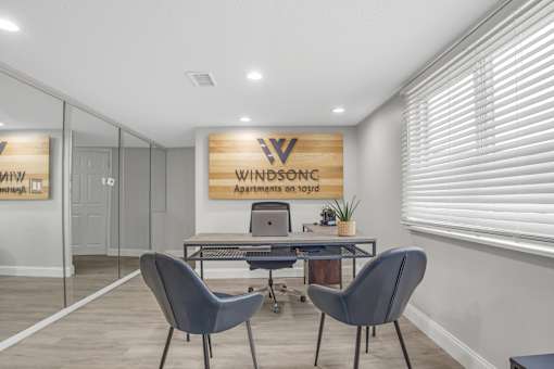 A room with a desk and chairs with a sign that says "Windsonc Apartments on 1093".