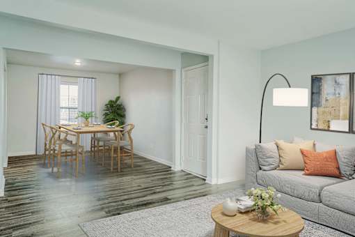 A living room with a grey couch, a wooden table, and a plant.