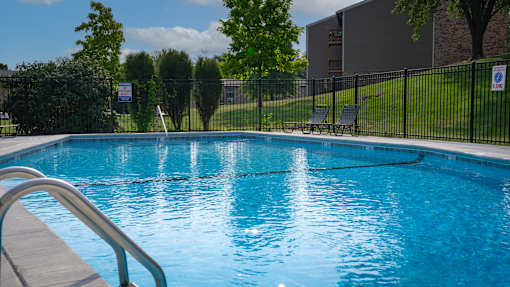 A pool with a metal railing in front of it.