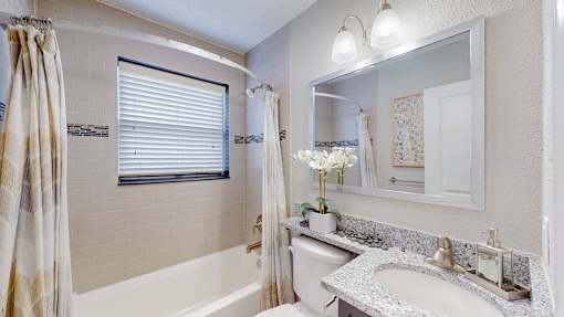 A bathroom with a white tub, sink, and a mirror.