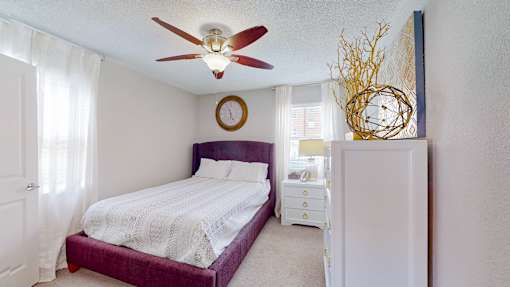 A bedroom with a purple bed and a white dresser.