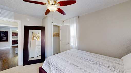 A bedroom with a white bed and a ceiling fan.