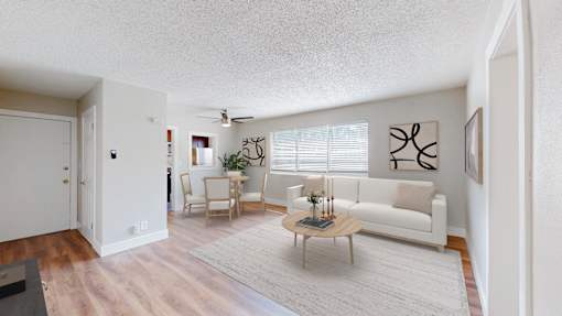 A living room with a white couch, a coffee table, and a painting on the wall.