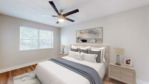 A bedroom with a bed, nightstand, and a ceiling fan.