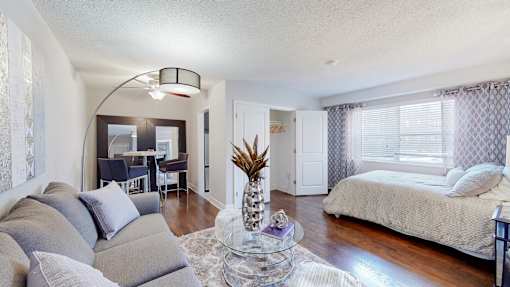 A living room with a grey couch and a pineapple on a glass table.