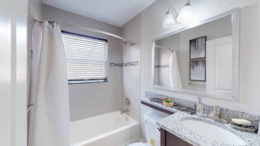 A bathroom with a white tub, sink, and mirror.