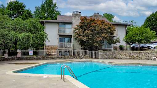 A swimming pool in front of a two-story building.