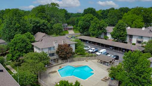 A large house with a pool in the middle of a wooded area.