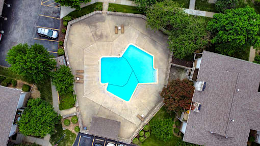 An aerial view of a swimming pool surrounded by a concrete patio and a grassy area.