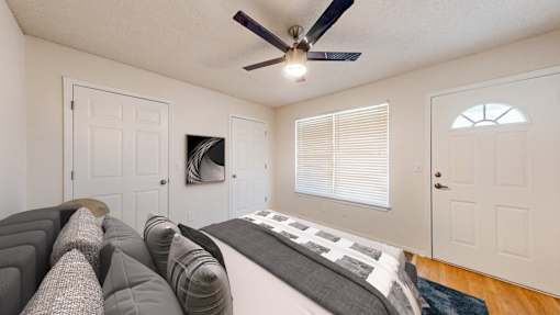 A bedroom with a bed, pillows, and a ceiling fan.