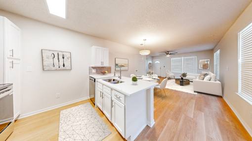 A kitchen with white cabinets and a wooden floor.