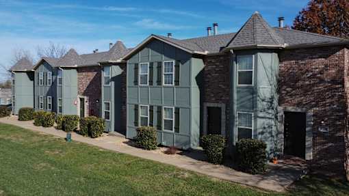 A row of houses with green siding and a brick chimney.