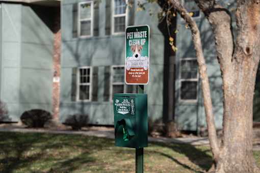 A green trash can with a sign that says "Pet Waste Pick Up" on it.