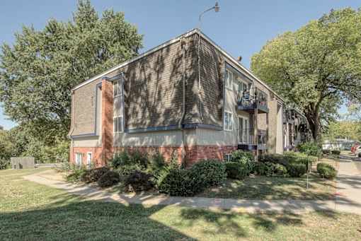 the front of a brick house with trees and a sidewalk