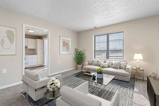 A living room with a white couch, a glass coffee table, and a plant.
