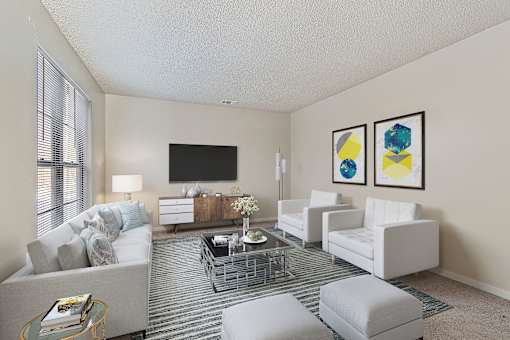 A living room with a grey sofa, a white armchair, a grey ottoman, a glass coffee table, a television, and two framed pictures on the wall.