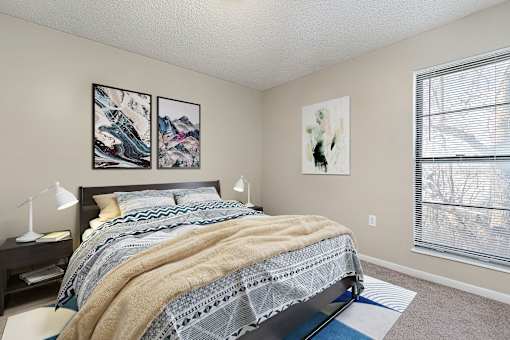 A bedroom with a bed, nightstand, and two pictures on the wall.