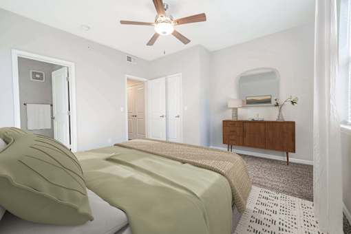 A bedroom with a bed, a dresser, and a ceiling fan.