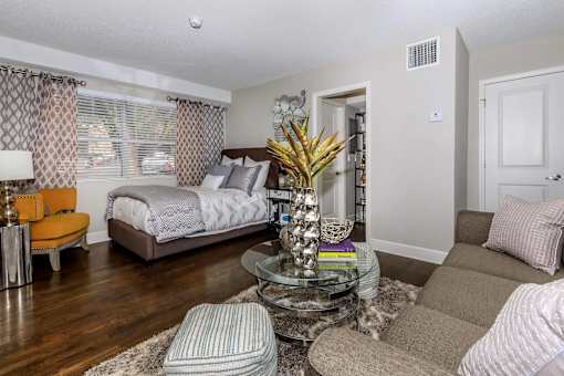 A bedroom with a bed, a chair, a couch, and a potted plant.