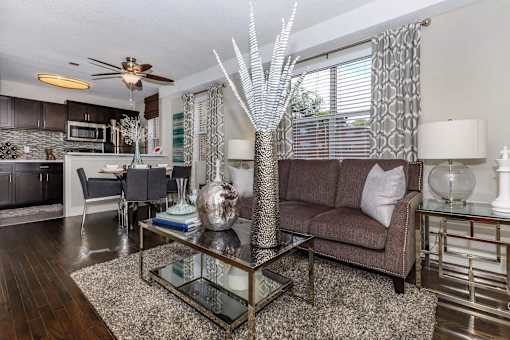 A modern living room with a glass coffee table and a brown couch.