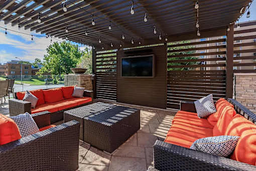 A patio with a couch, chairs, and a television.