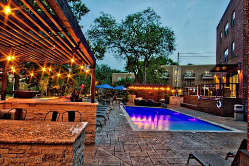 A pool area with a stone wall and a pergola.