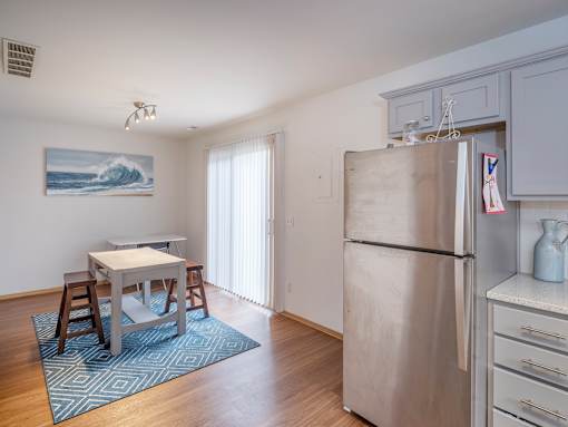 A kitchen with a refrigerator, table, and chairs.