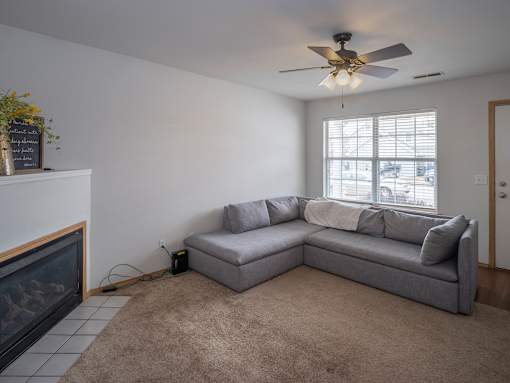A living room with a grey couch and a fireplace.