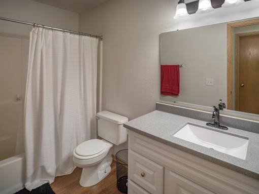 A white toilet with a white sink and a white shower curtain in a bathroom.