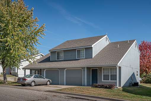 A house with a grey roof and a car parked in front.