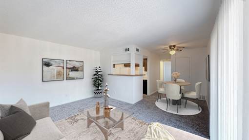 A living room with a grey couch and a glass coffee table.