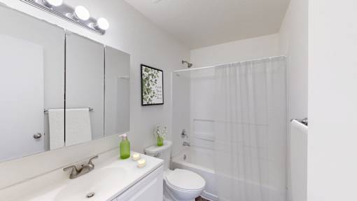 A white bathroom with a toilet, sink, and shower.
