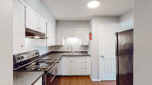 an empty kitchen with stainless steel appliances and white cabinets