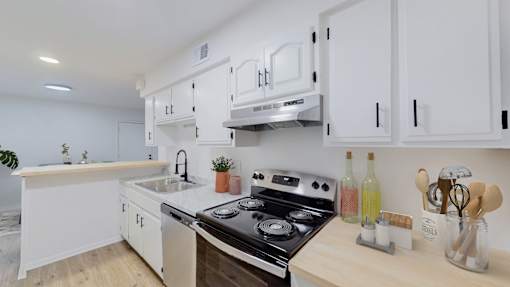 A modern kitchen with white cabinets and a black stove top.