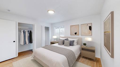 A bedroom with a large bed, a nightstand, and a wardrobe.