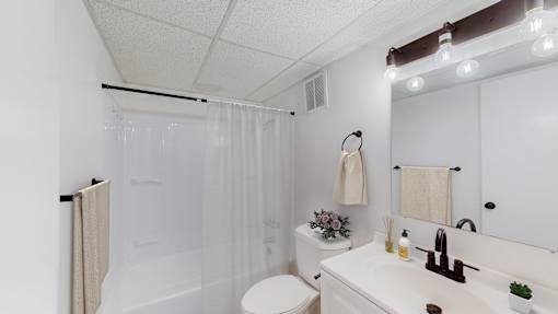 A white bathroom with a toilet, sink, and shower curtain.