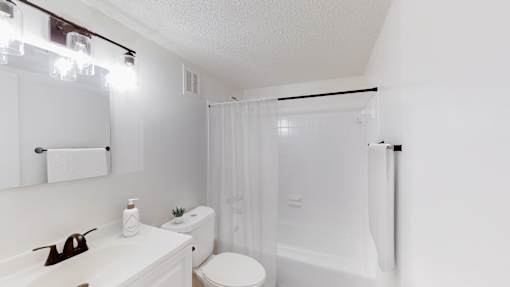 A white bathroom with a toilet, sink, and shower.