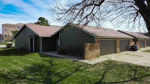 A house with a green lawn and a tree in front.