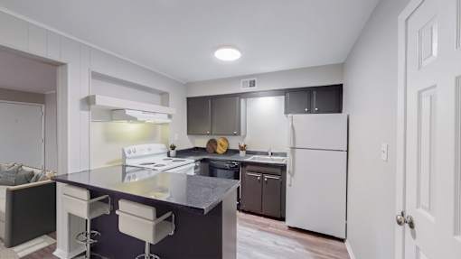 A kitchen with a white fridge and a black counter top.
