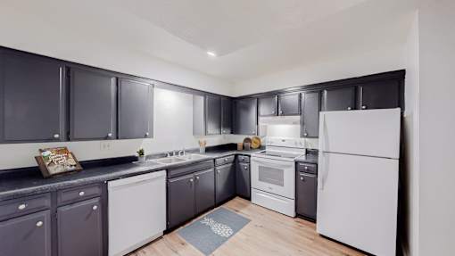 A kitchen with white appliances and black cabinets.
