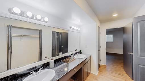 A bathroom with a vanity, sink, mirror, and lights.