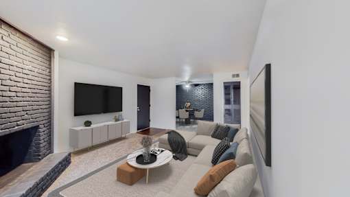 A modern living room with a brick fireplace and a large flat screen TV mounted on the wall.