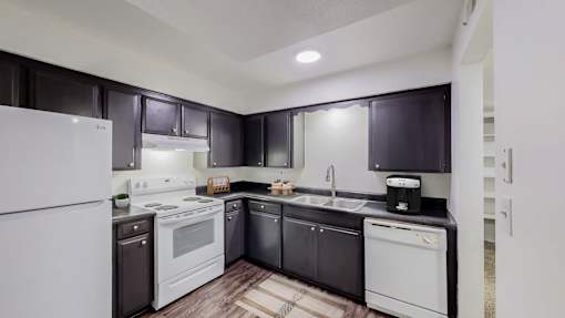 A modern kitchen with white appliances and dark wood cabinets.