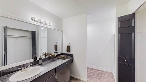 A bathroom with a sink, mirror, and towel rack.