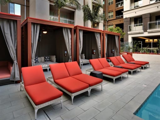 A row of red lounge chairs are arranged on a patio at West Park Apartments, San Diego